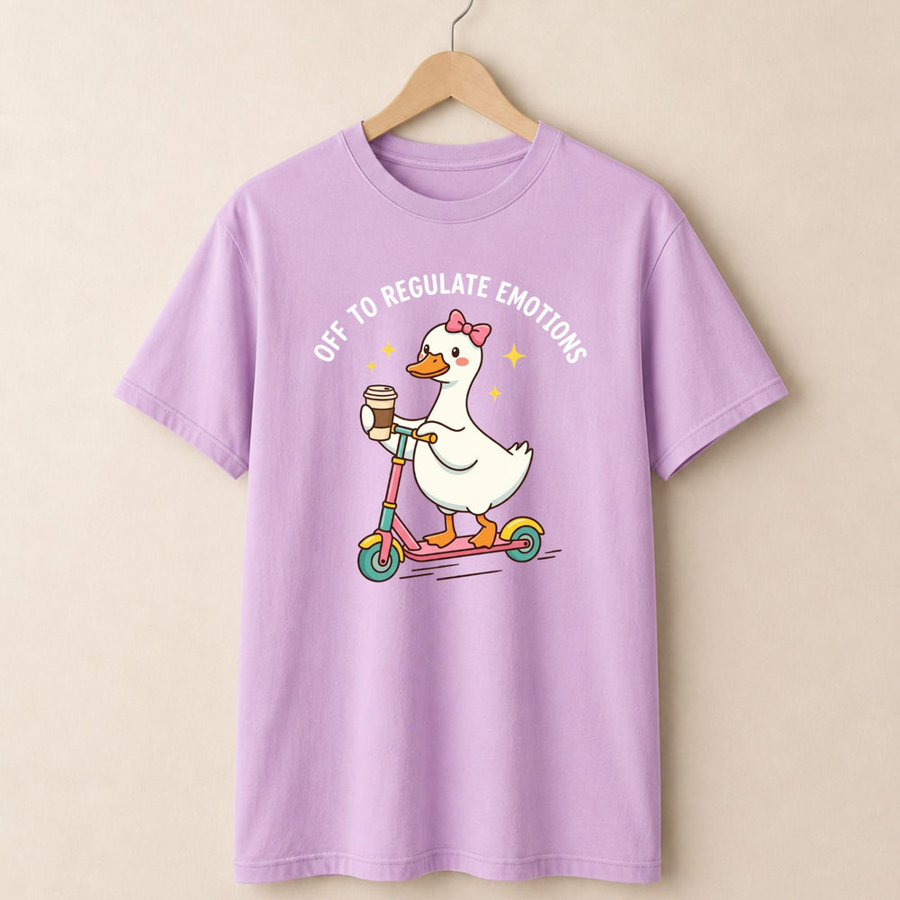 Purple t-shirt with a cartoon duck on a scooter and text, hanging on a beige wall.